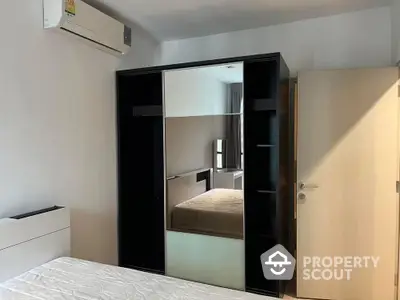 Modern bedroom with sleek mirrored wardrobe and air conditioning unit