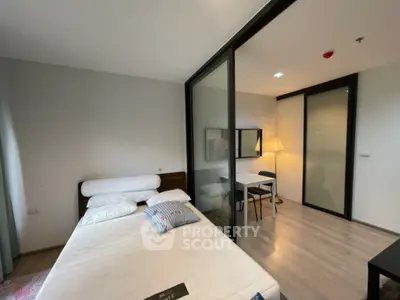 Modern bedroom with glass partition and study area, featuring sleek design and ample natural light.
