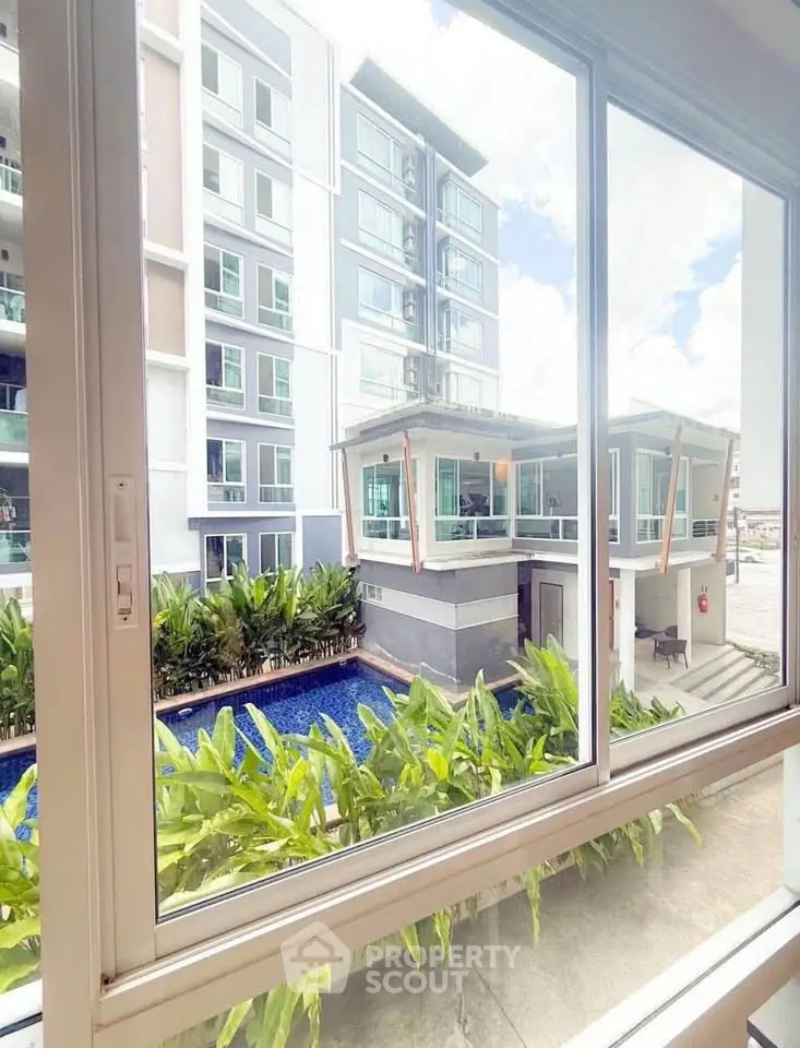 Modern apartment view with pool and lush greenery from window