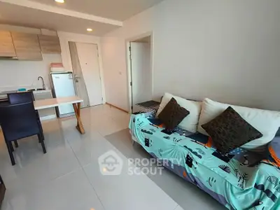 Modern living room with open kitchen, stylish sofa, and dining area in a cozy apartment.
