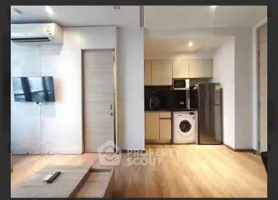 Modern apartment interior with open kitchen and living area featuring wooden flooring and sleek appliances.