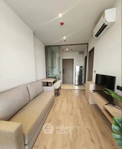Modern living room with sleek design, featuring a comfortable sofa, air conditioning, and stylish wooden flooring.
