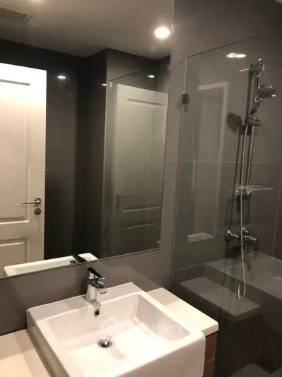 Modern bathroom with sleek fixtures and glass shower enclosure in contemporary apartment.