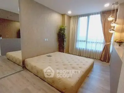 Spacious bedroom with large window and modern decor in a stylish apartment.
