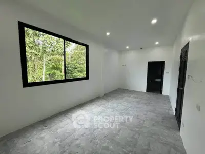 Spacious unfurnished room with large window and garden view