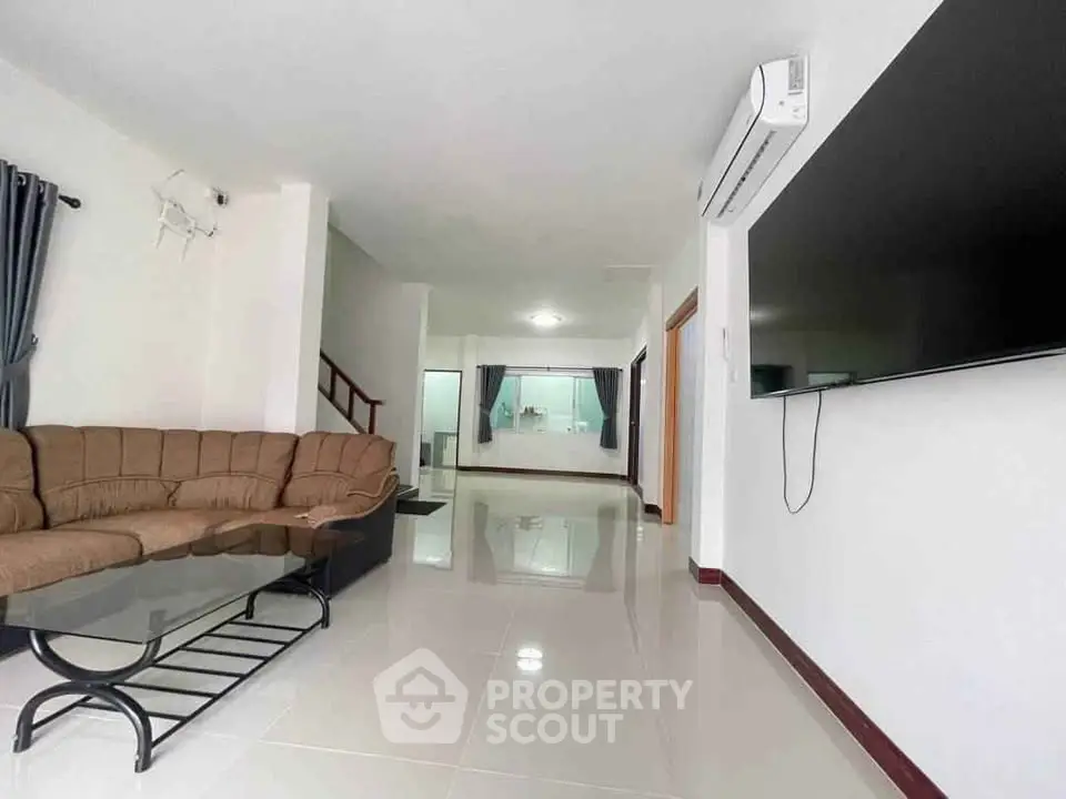 Spacious modern living room with sleek design and large TV, perfect for family gatherings.