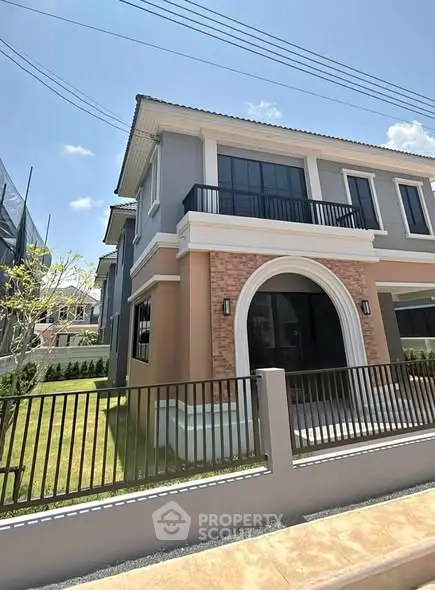 Modern two-story house with elegant facade and spacious balcony in sunny neighborhood.
