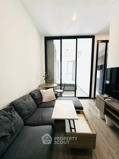 Modern living room with sleek furniture and glass partition leading to bedroom