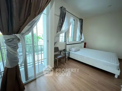 Bright bedroom with balcony access and elegant curtains, featuring a minimalist design and wooden flooring.