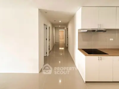 Spacious modern kitchen with sleek cabinetry and glossy tile flooring in a bright apartment.
