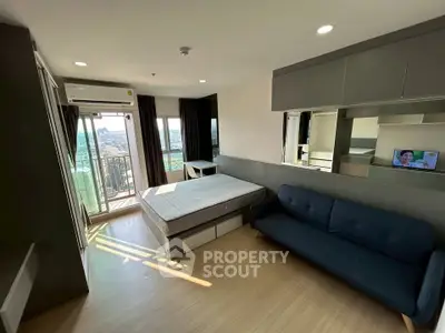 Modern studio apartment with balcony and city view, featuring a cozy bed and stylish sofa.