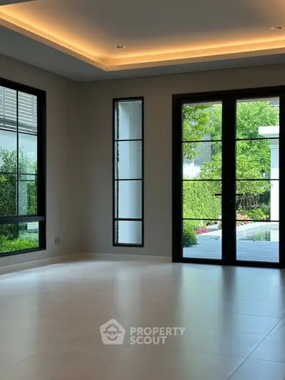 Spacious modern living room with large windows and garden view, perfect for natural light lovers.