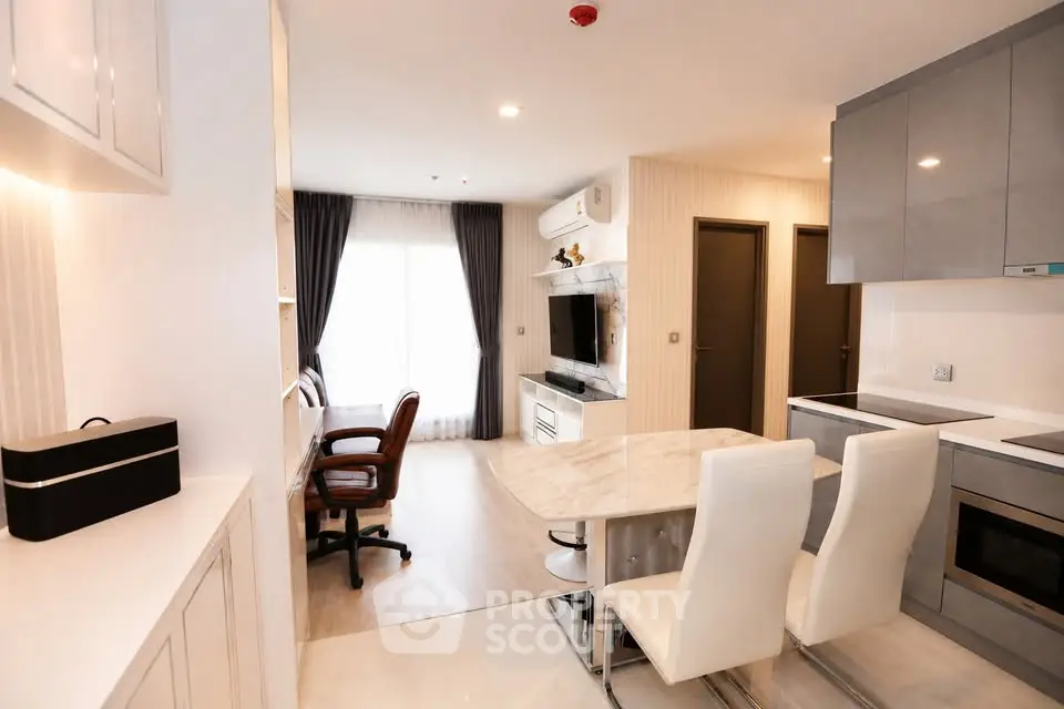 Modern open-plan living room with stylish kitchen and dining area, featuring sleek furniture and natural light.