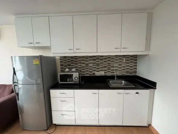 Modern kitchen with sleek cabinetry and stainless steel fridge in a compact layout.
