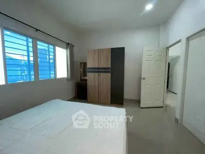 Spacious bedroom with modern wardrobe and large window for natural light.
