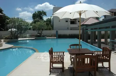 Luxurious outdoor pool area with elegant seating and umbrella, perfect for relaxation and entertainment.