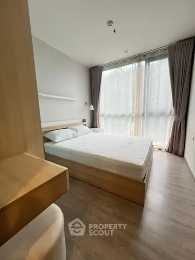 Modern bedroom with large window and natural light, featuring a minimalist design and cozy atmosphere.