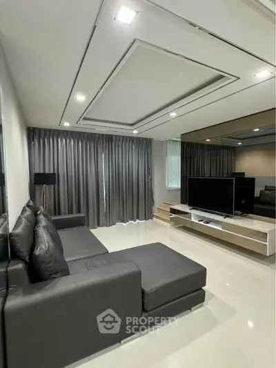 Modern living room with sleek black sofa and large TV, featuring elegant curtains and glossy flooring.