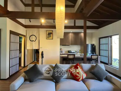 Charming open-layout living room with modern kitchen, featuring wooden beams and stylish decor.