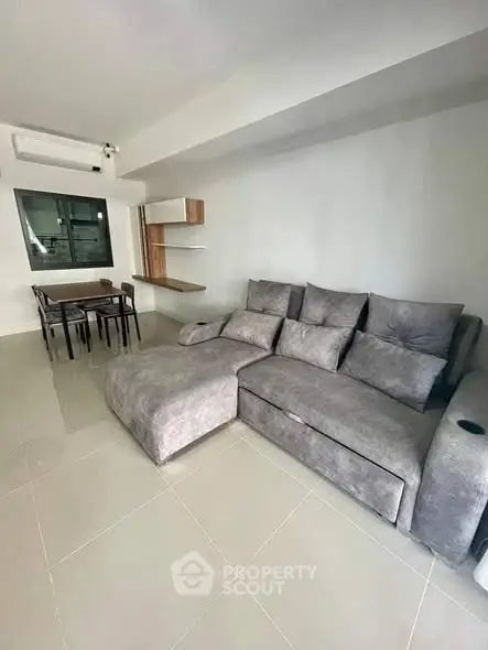 Modern living room with gray sectional sofa and dining area, open layout design.