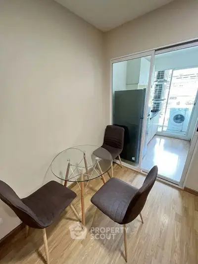 Cozy dining area with glass table and chairs, adjacent to modern kitchen with appliances.