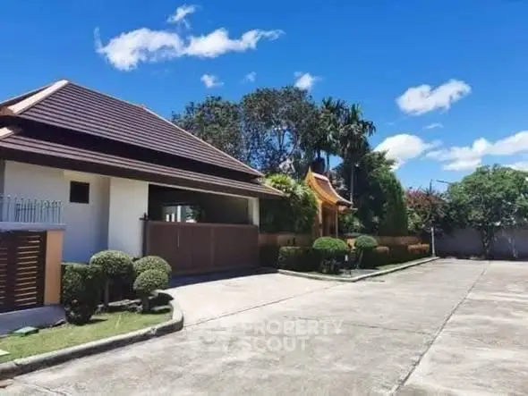 Charming residential property with spacious driveway and lush greenery under clear blue sky.