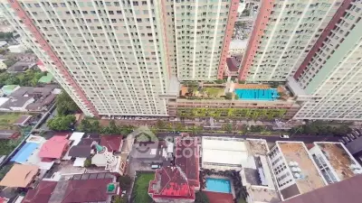 Stunning aerial view of high-rise residential building with rooftop pool and lush surroundings.
