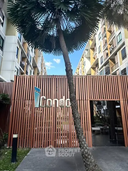 Modern condo entrance with stylish wooden facade and palm tree
