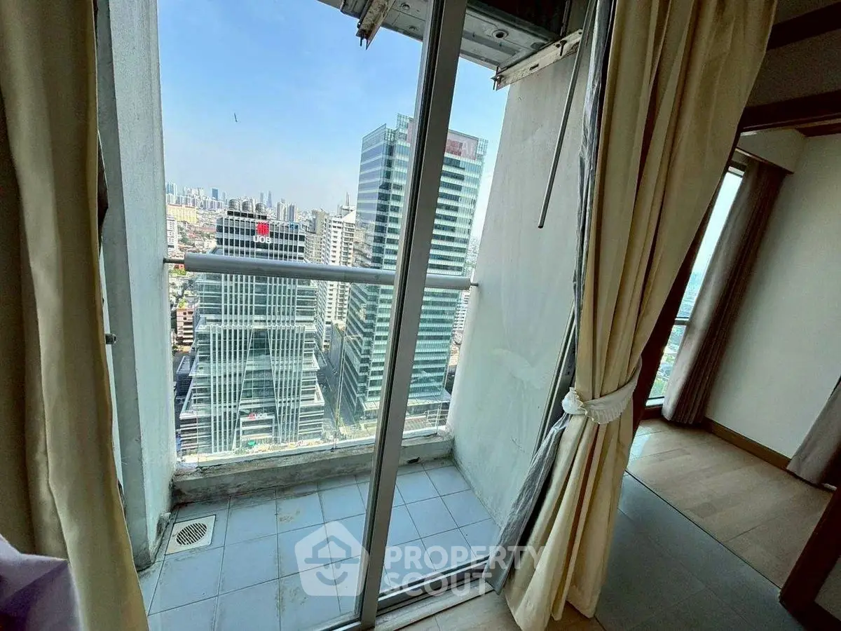 High-rise apartment with stunning city view from balcony, featuring floor-to-ceiling windows and elegant curtains.