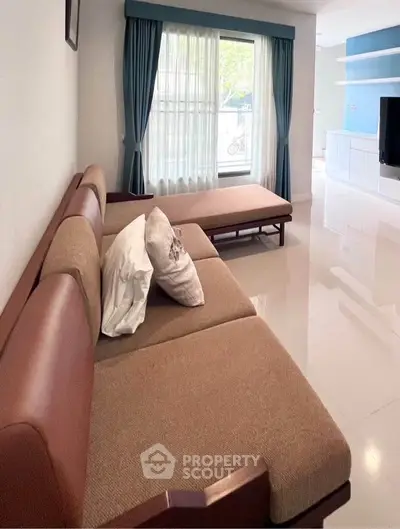 Spacious living room with modern sofa and large window, perfect for relaxation and entertainment.