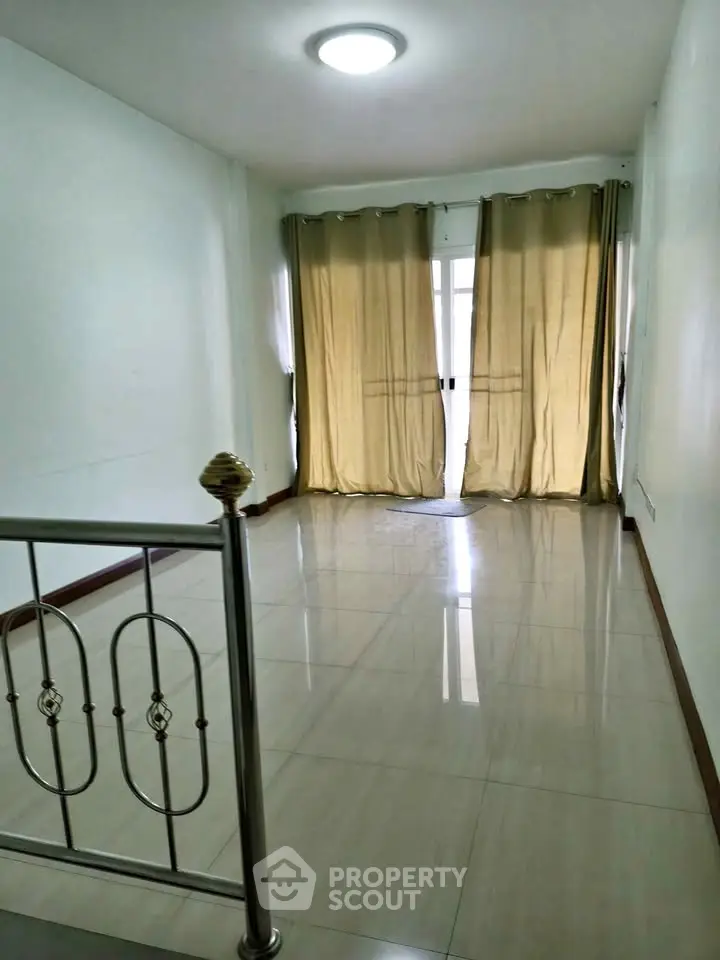 Spacious living room with elegant railing and large window for natural light.