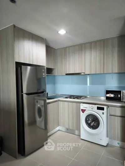 Modern kitchen with sleek appliances including fridge, washing machine, and microwave in stylish cabinetry.