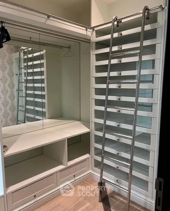 Luxurious walk-in closet with mirrored walls and ladder for easy access.
