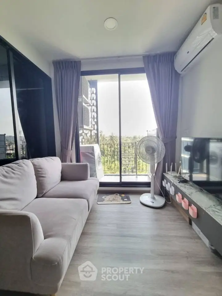 Modern living room with balcony view, featuring cozy sofa and air conditioning.