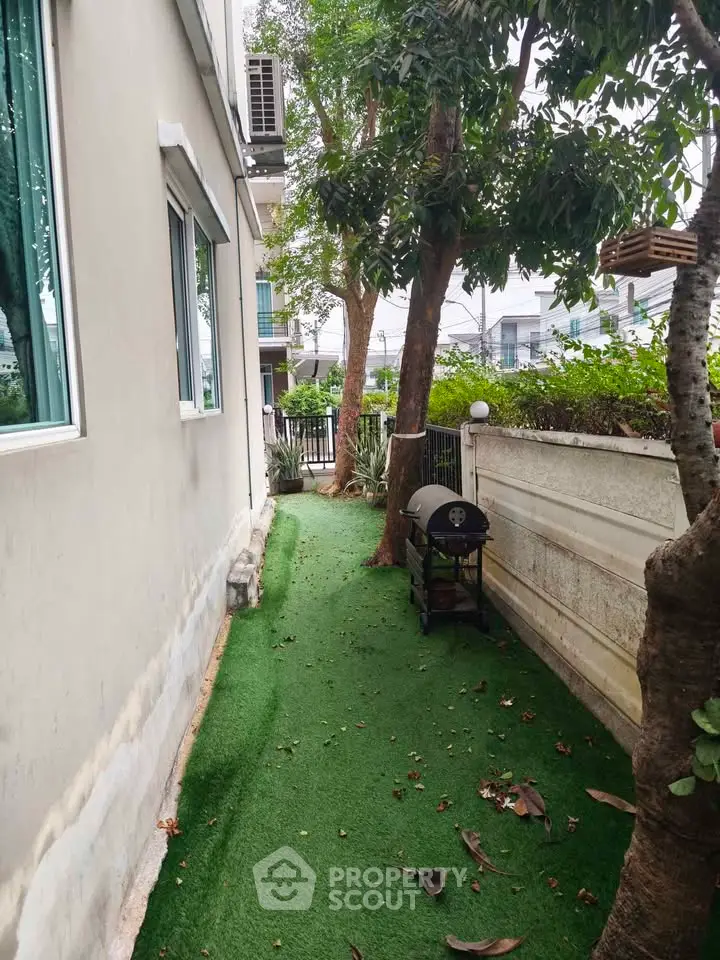 Charming side garden with artificial grass and barbecue grill, perfect for outdoor relaxation.
