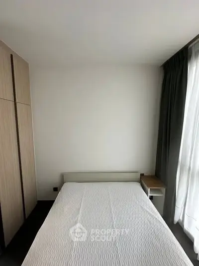 Modern minimalist bedroom with sleek wardrobe and large window for natural light.