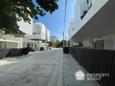 Modern residential street with contemporary white buildings and clear blue sky