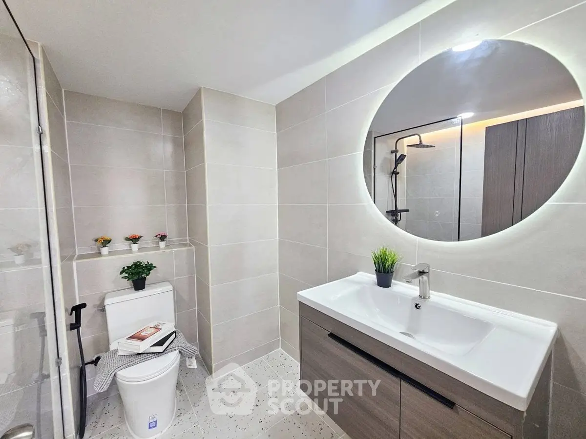 Modern bathroom with sleek fixtures and stylish lighting, featuring a round mirror and elegant vanity.
