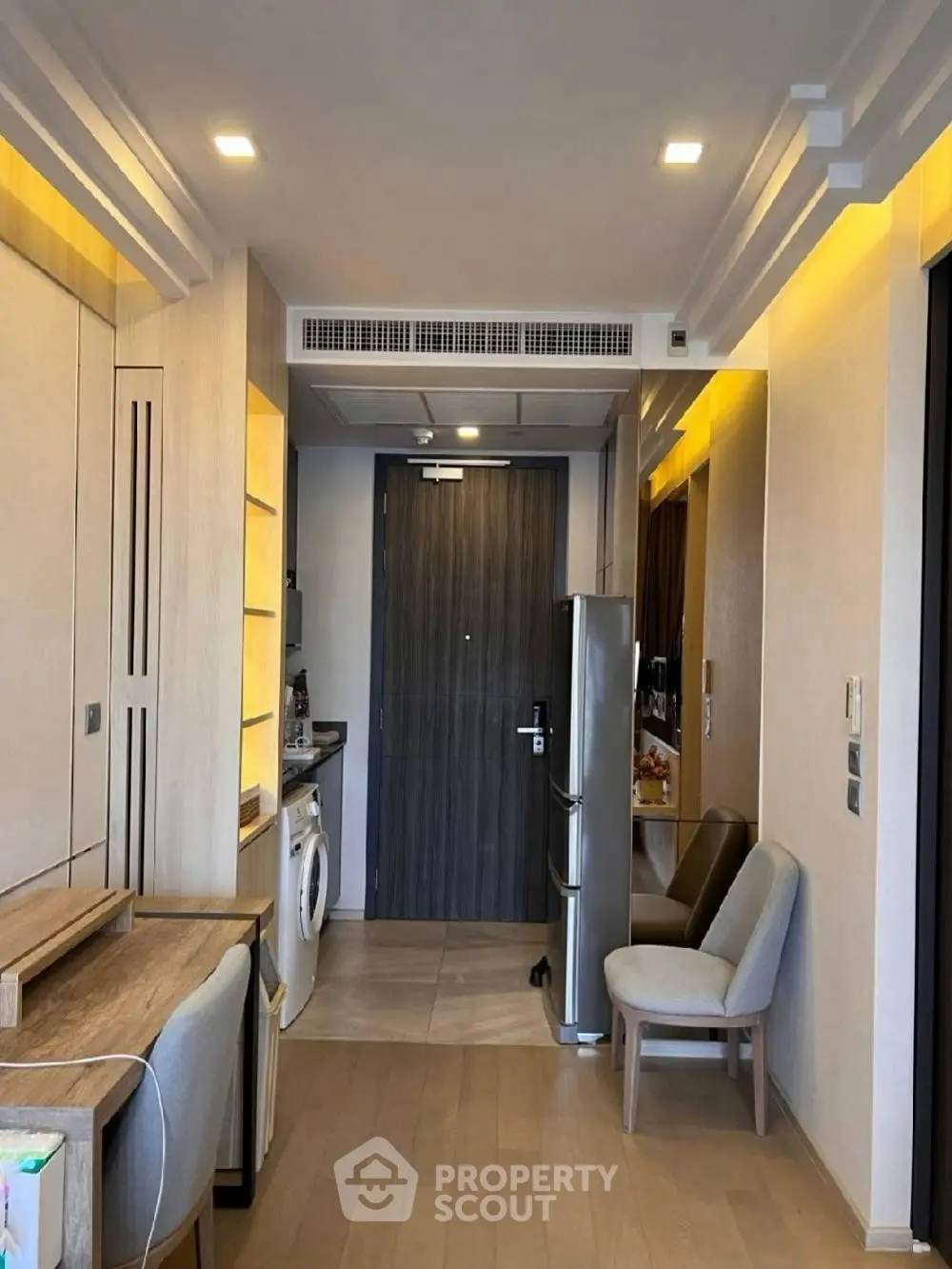 Modern apartment interior with wooden flooring, compact kitchen, and stylish furniture.