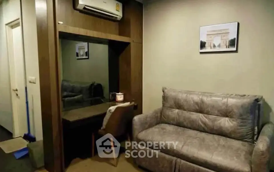 Cozy living room with modern sofa and wall art, featuring a stylish mirror and air conditioning.