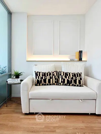 Modern living room with stylish sofa and decorative pillows, featuring elegant wall paneling and wooden flooring.