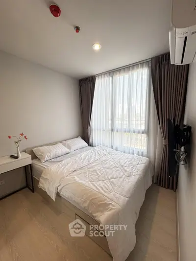 Cozy bedroom with natural light, modern decor, and air conditioning in a stylish apartment.