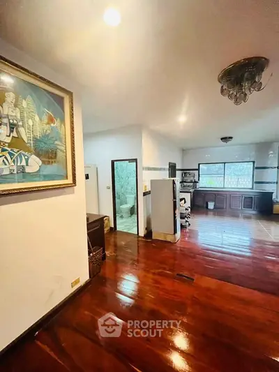 Spacious open-layout living area with wooden flooring and modern kitchen.