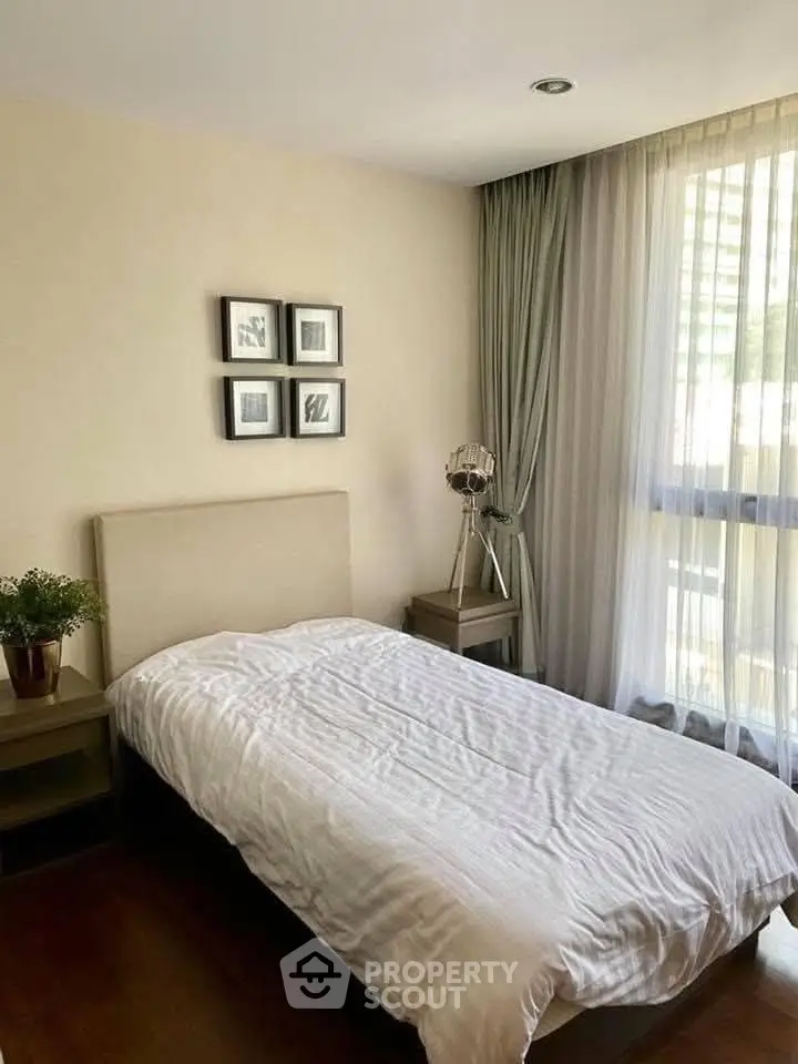 Cozy bedroom with natural light, modern decor, and elegant curtains in a stylish apartment.