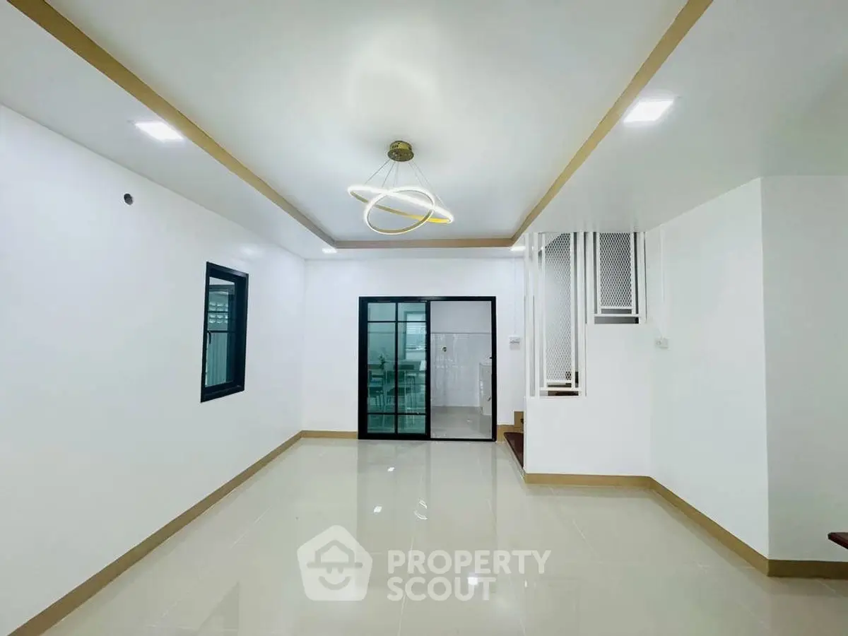 Spacious modern living room with sleek lighting and tiled flooring, perfect for contemporary living.