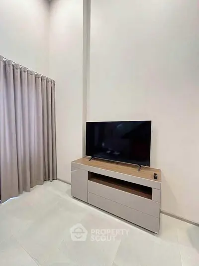 Modern living room with sleek TV stand and curtains, perfect for cozy entertainment.