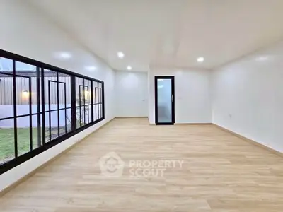 Spacious empty room with large windows and wooden flooring, perfect for customization.