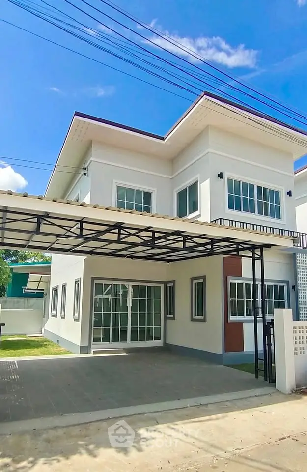 Modern two-story house with carport and large windows under a clear blue sky.