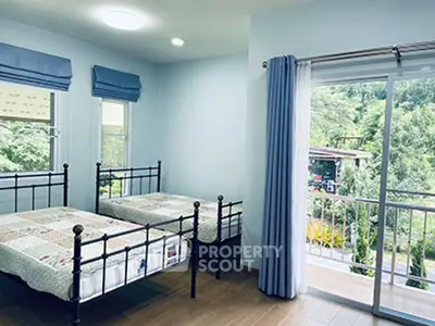 Charming bedroom with twin beds and balcony overlooking lush greenery.