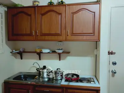 Cozy kitchen with wooden cabinets and stainless steel countertop featuring stove and sink.